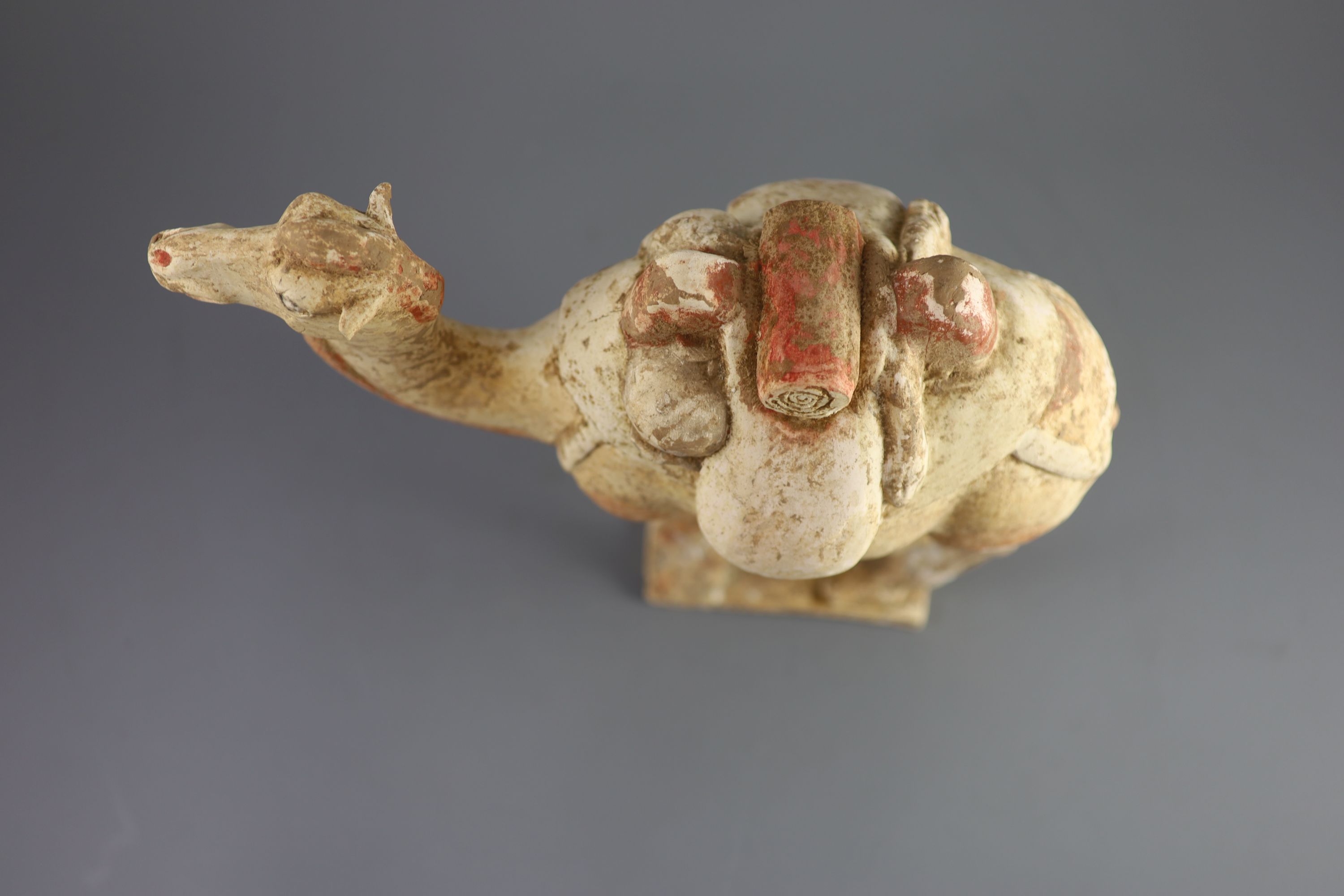 A Chinese pottery model of a Bactrian camel and a similar head of a man, Tang Dynasty, 28 cm and 16.5 cm high including bases